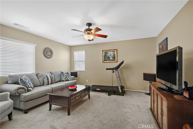 living room with baseboards, a ceiling fan, visible vents, and light colored carpet