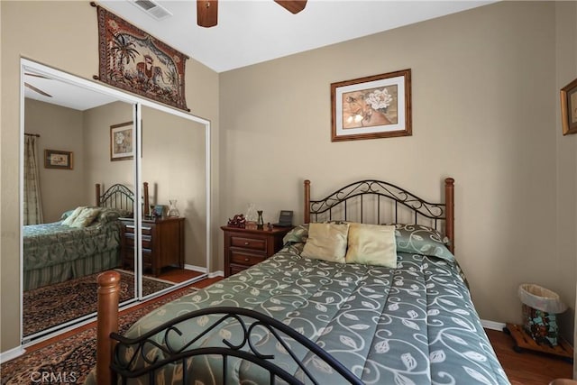 bedroom with wood finished floors, a closet, ceiling fan, baseboards, and visible vents