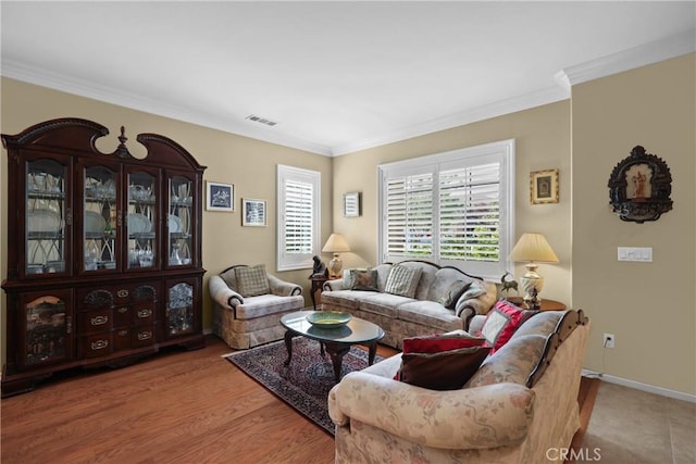 living room with ornamental molding, visible vents, baseboards, and wood finished floors