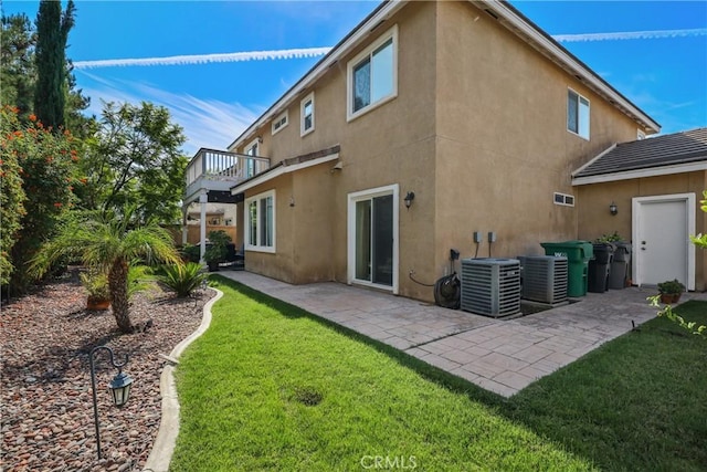 back of property with a patio, a yard, a balcony, and stucco siding