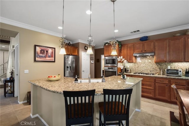 kitchen with a kitchen island with sink, under cabinet range hood, stainless steel appliances, visible vents, and hanging light fixtures