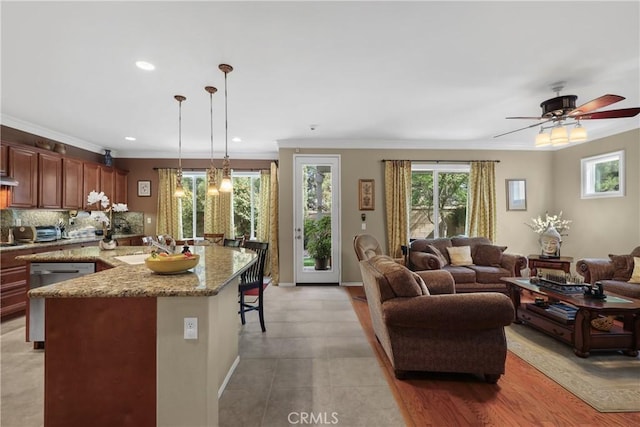 kitchen featuring pendant lighting, tasteful backsplash, stainless steel dishwasher, open floor plan, and a sink