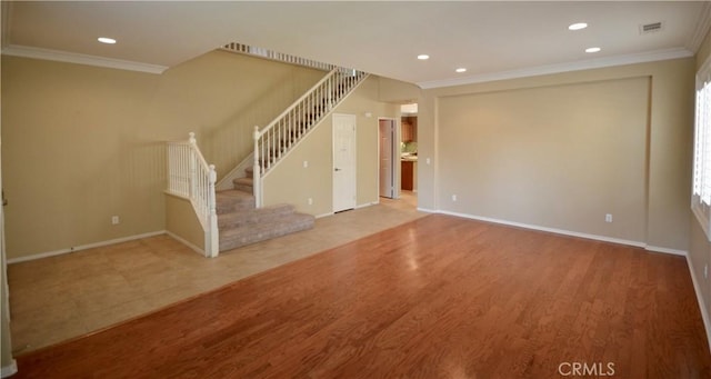 unfurnished living room with stairway, wood finished floors, baseboards, and ornamental molding