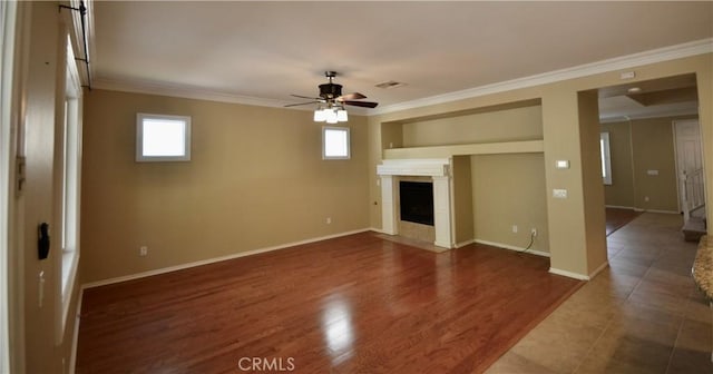 unfurnished living room with a fireplace with flush hearth, baseboards, visible vents, ceiling fan, and crown molding