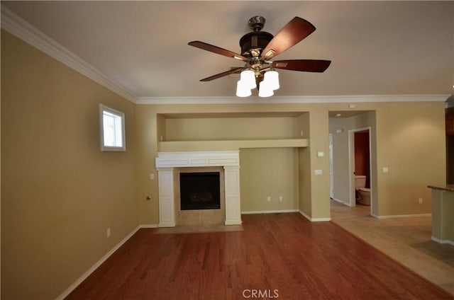 unfurnished living room featuring wood finished floors, crown molding, baseboards, a fireplace, and ceiling fan