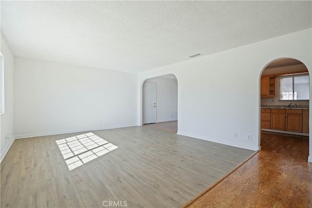 spare room with a textured ceiling, light hardwood / wood-style flooring, and sink