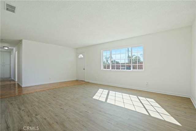 unfurnished room with a textured ceiling and hardwood / wood-style floors