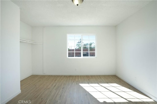 spare room featuring wood-type flooring and a textured ceiling