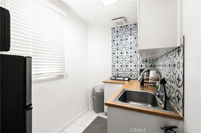 kitchen featuring butcher block counters, stainless steel refrigerator, and sink