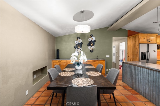 dining area featuring lofted ceiling with beams and dark tile patterned flooring