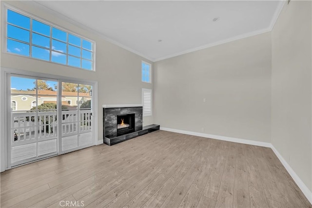 unfurnished living room with a premium fireplace, light wood-type flooring, and ornamental molding