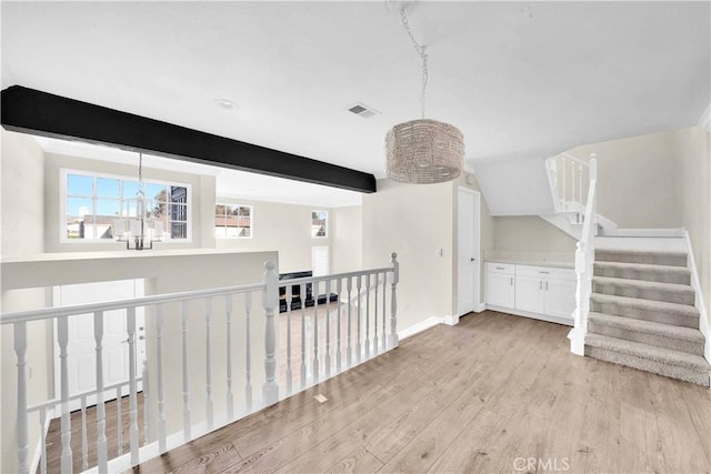 interior space featuring a chandelier, beamed ceiling, and light hardwood / wood-style floors