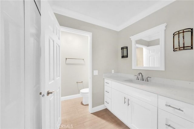 bathroom featuring vanity, toilet, wood-type flooring, and crown molding