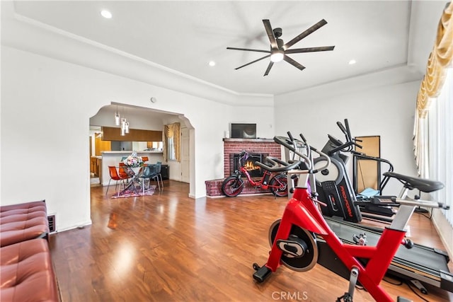 exercise area with hardwood / wood-style floors, ceiling fan, and a brick fireplace