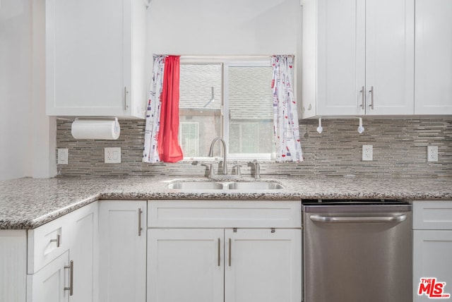 kitchen featuring light stone countertops, sink, tasteful backsplash, stainless steel dishwasher, and white cabinets