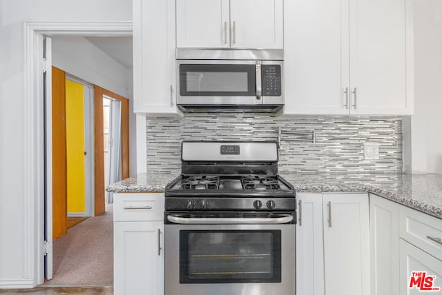 kitchen featuring light stone countertops, stainless steel appliances, and white cabinetry