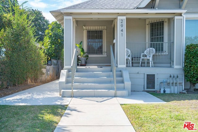 property entrance with covered porch and a lawn