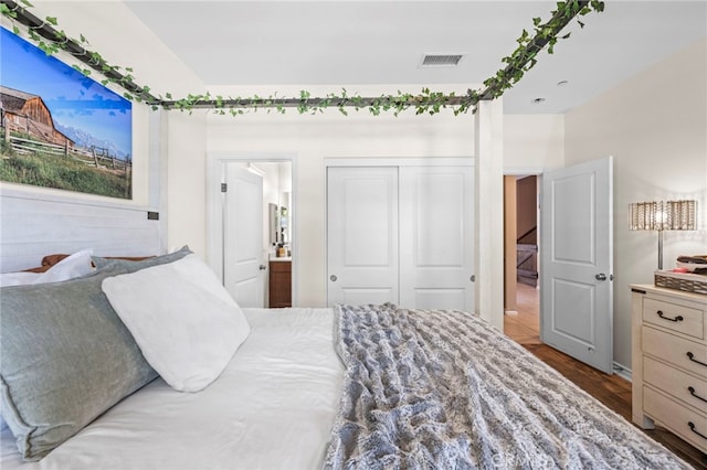 bedroom featuring wood-type flooring, ensuite bathroom, and a closet