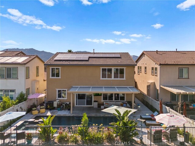 back of house featuring a mountain view, solar panels, and a patio