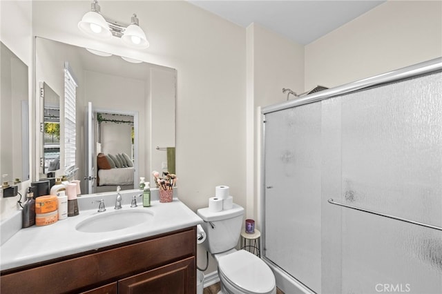 bathroom featuring toilet, vanity, and a shower with door