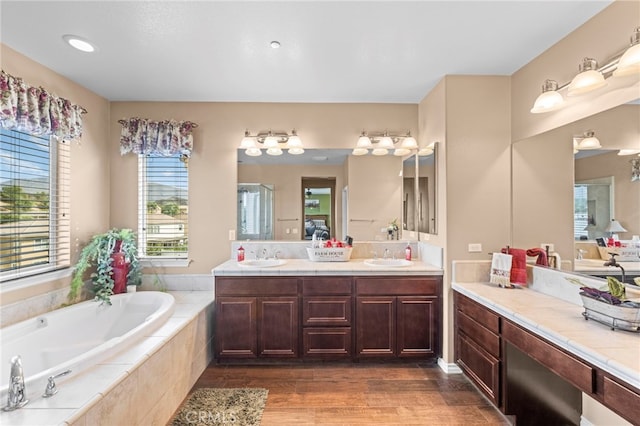 bathroom featuring vanity, tiled tub, and wood-type flooring