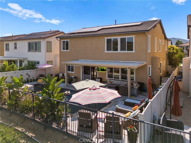 rear view of property featuring an outdoor living space and solar panels