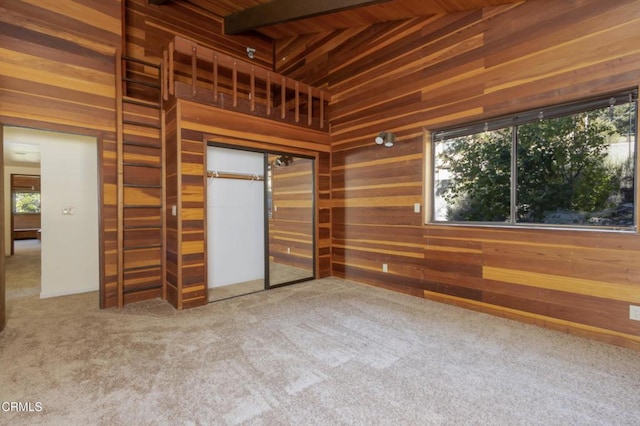 unfurnished bedroom featuring carpet floors, multiple windows, and wooden walls