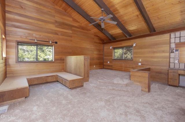 unfurnished office featuring beamed ceiling, light colored carpet, a healthy amount of sunlight, and wood walls