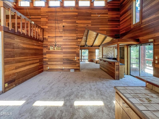 interior space featuring wood walls, lofted ceiling, wood ceiling, and an inviting chandelier