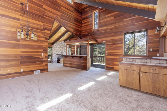 kitchen with tile countertops, decorative light fixtures, beam ceiling, and light colored carpet