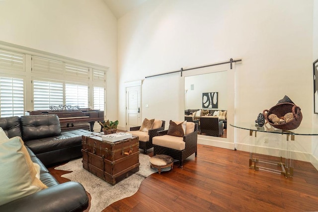 living room with hardwood / wood-style flooring, a barn door, and high vaulted ceiling