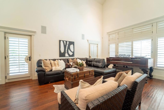 living room with a towering ceiling and dark wood-type flooring