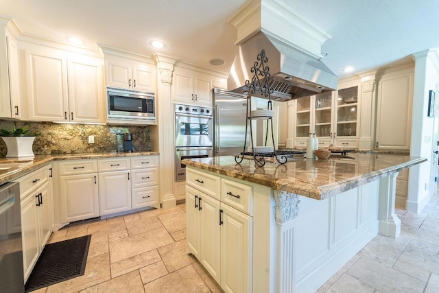 kitchen with backsplash, a kitchen island, light stone counters, white cabinetry, and stainless steel appliances