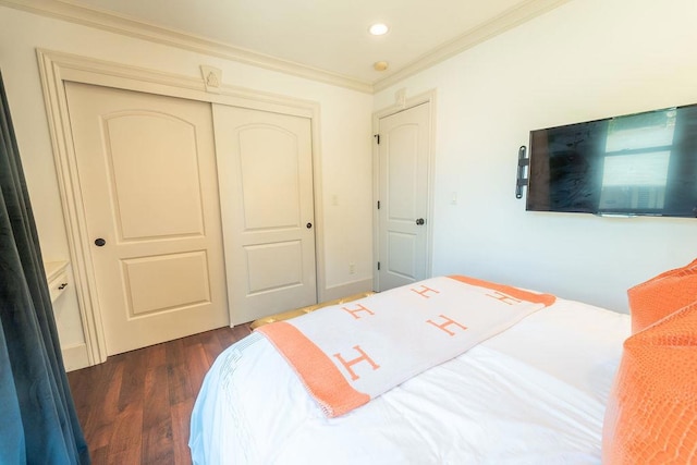 bedroom featuring dark hardwood / wood-style flooring, ornamental molding, and a closet