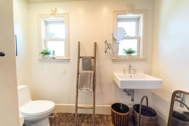 bathroom with plenty of natural light, toilet, and sink