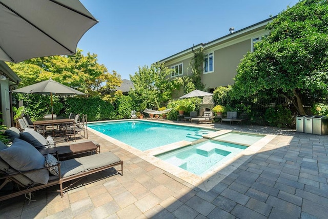 view of swimming pool featuring an in ground hot tub, a patio, and exterior fireplace