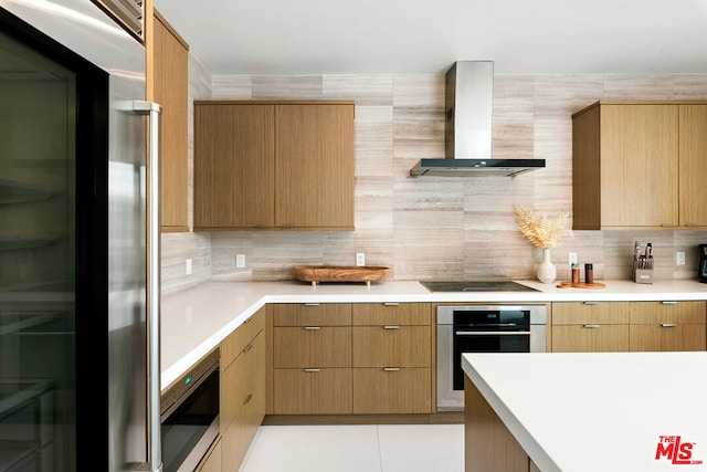 kitchen featuring built in appliances, wall chimney range hood, and decorative backsplash