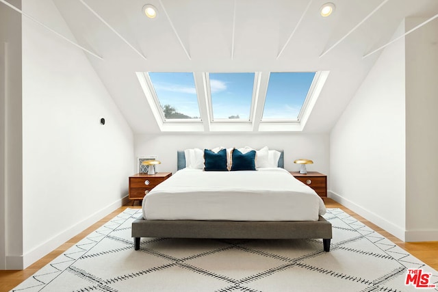 bedroom with light hardwood / wood-style flooring and lofted ceiling with skylight