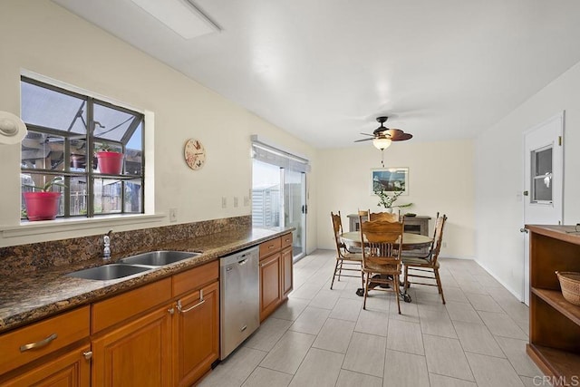 kitchen featuring stainless steel dishwasher, ceiling fan, dark stone counters, and sink