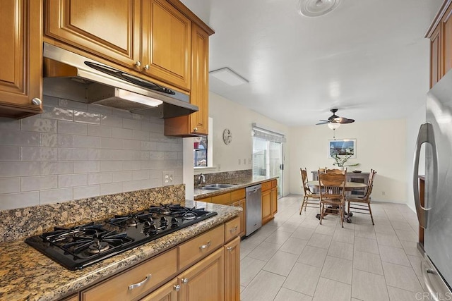 kitchen featuring dark stone counters, decorative backsplash, ceiling fan, and stainless steel appliances