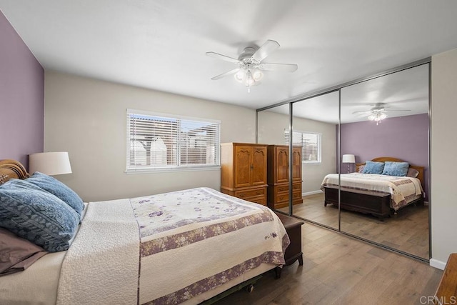 bedroom with hardwood / wood-style floors, a closet, multiple windows, and ceiling fan