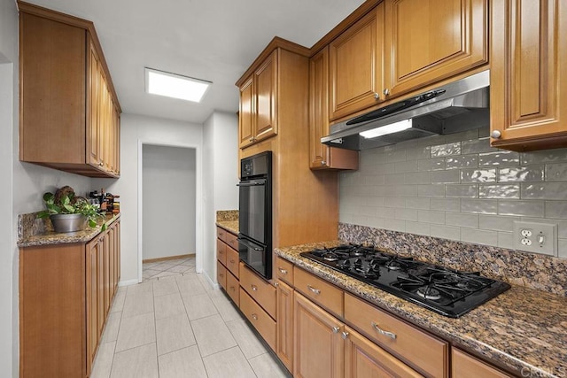 kitchen featuring black appliances, light tile patterned flooring, dark stone countertops, and tasteful backsplash