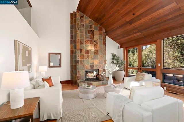 living room featuring a tiled fireplace, high vaulted ceiling, wooden ceiling, and hardwood / wood-style flooring