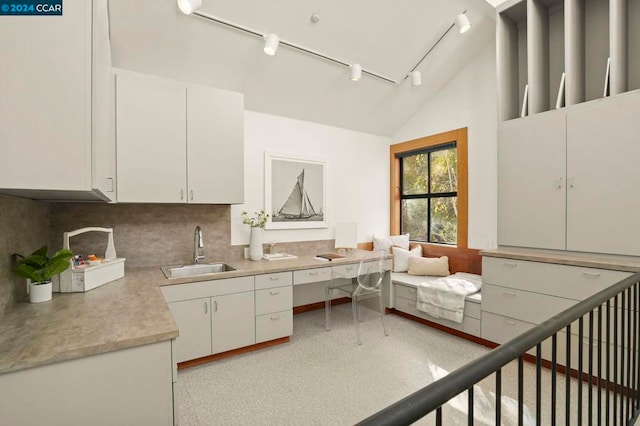 kitchen with decorative backsplash, white cabinetry, vaulted ceiling, and sink