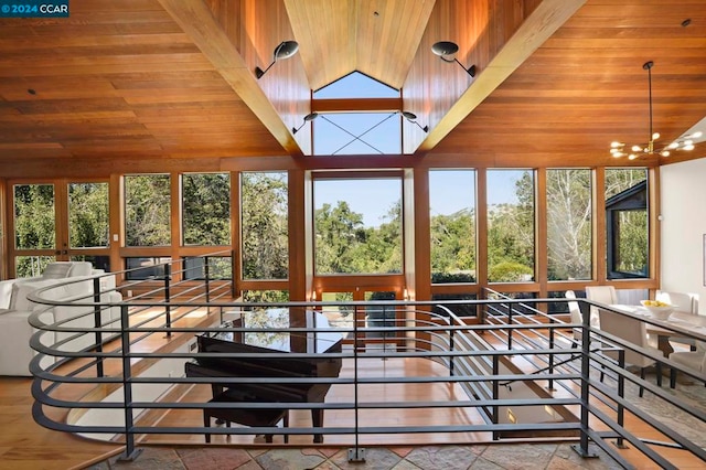 sunroom / solarium featuring a healthy amount of sunlight, wood ceiling, and an inviting chandelier