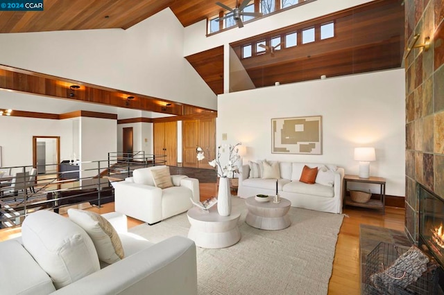 living room featuring a fireplace, high vaulted ceiling, wood ceiling, and light hardwood / wood-style flooring