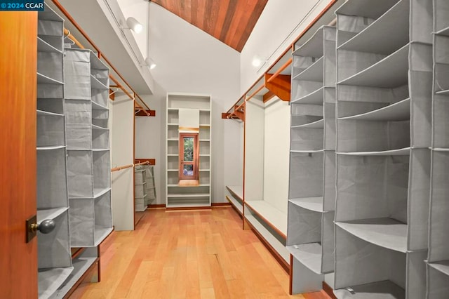 walk in closet with high vaulted ceiling and hardwood / wood-style flooring