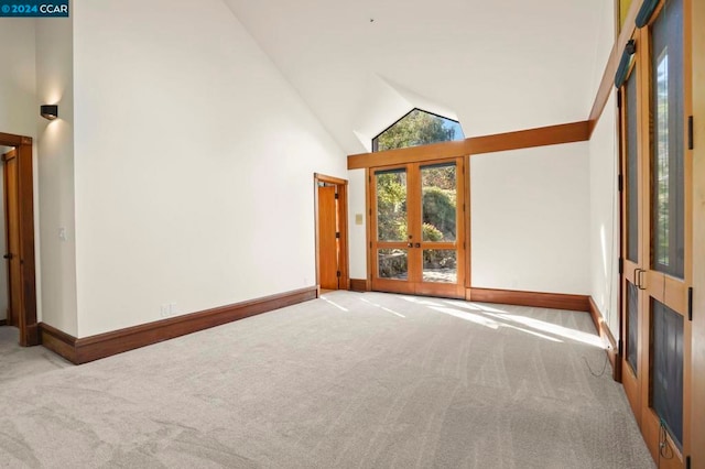 spare room featuring light carpet, french doors, and high vaulted ceiling