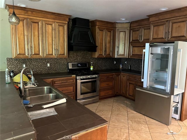kitchen with appliances with stainless steel finishes, backsplash, wall chimney exhaust hood, decorative light fixtures, and light tile patterned flooring