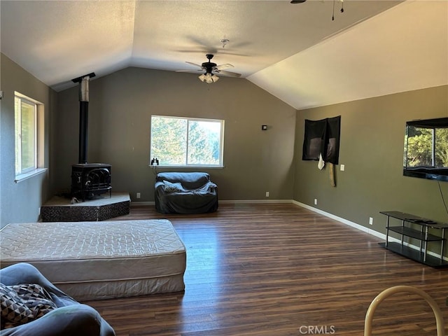 living room with lofted ceiling, ceiling fan, a wood stove, and dark wood-type flooring